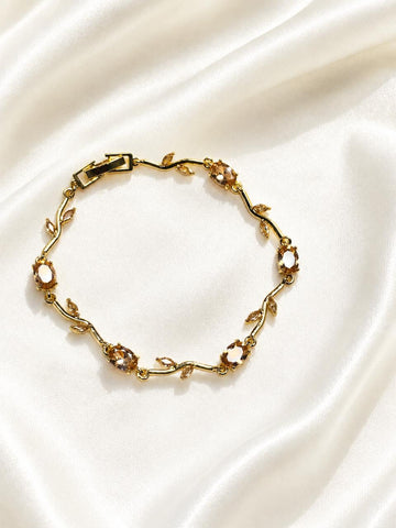 gold-plated vine bracelet features sparkling crystal stones and delicate leaf accents